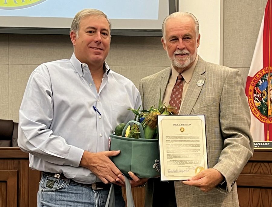 OKEECHOBEE -- Okeechobee County Commissioner Terry Burroughs (right) presented Mickey Bandi, of Florida Farm Bureau, with the proclamation for Farm City Week at the Nov. 9 commission meeting. Bandi presented Burroughs with some produce. [Photo by Katrina Elsken/Lake Okeechobee News]